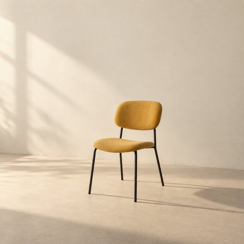 Chaise jaune à pieds noirs vue de trois quarts sur fond crème, avec une longue ombre